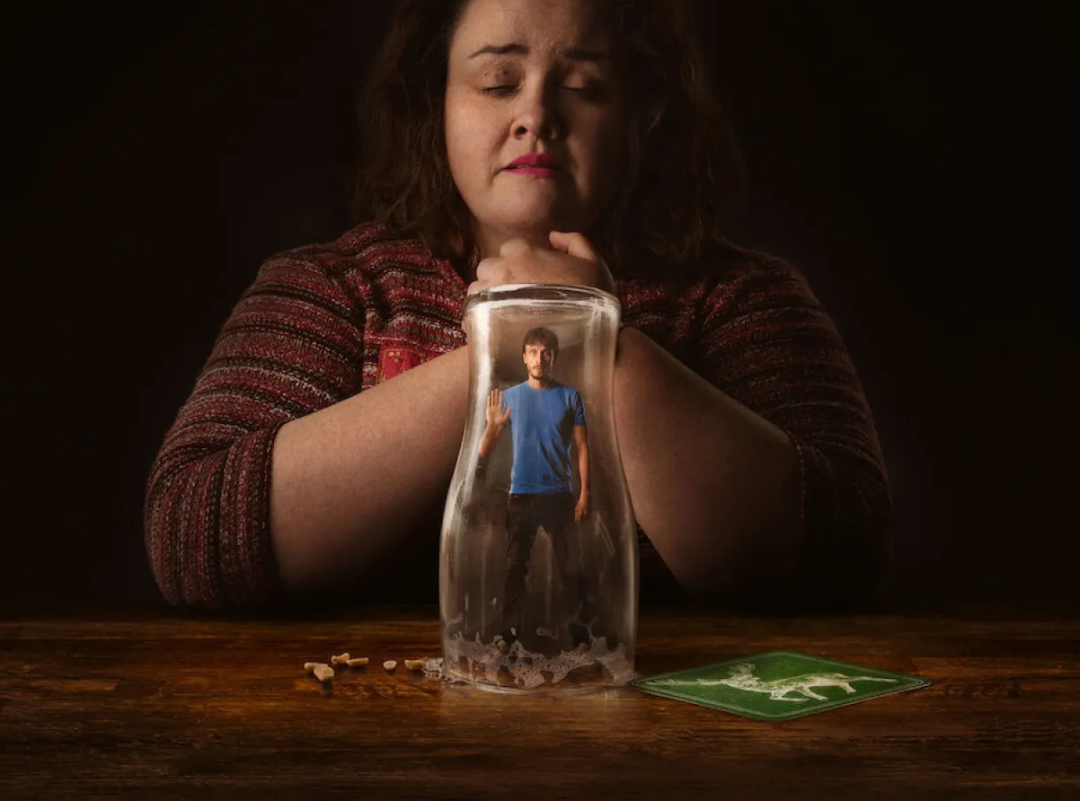 Na imagem a personagem Martha está rezando e o Donny está preso dentro de um pote de vidro.